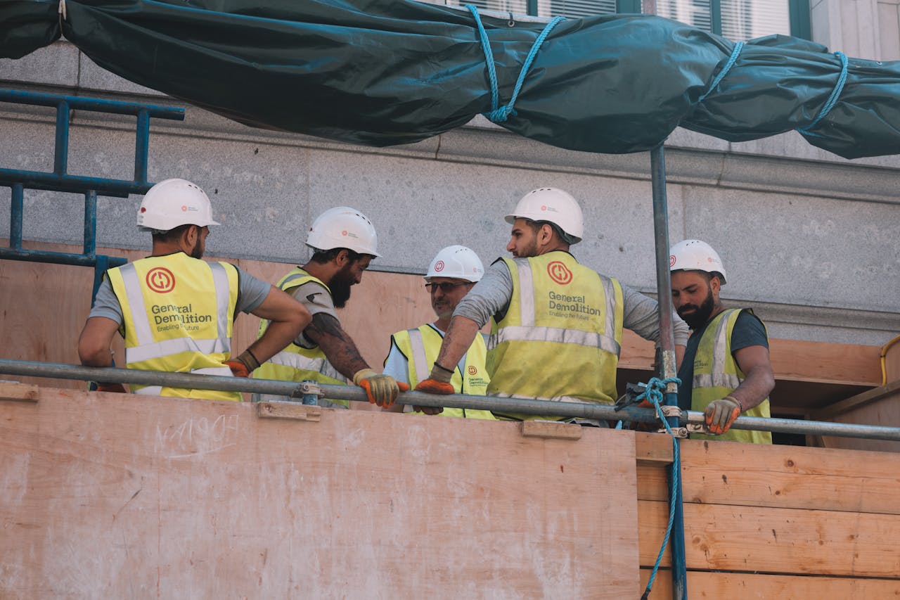 Group of construction workers in safety gear collaborating at a city construction site.