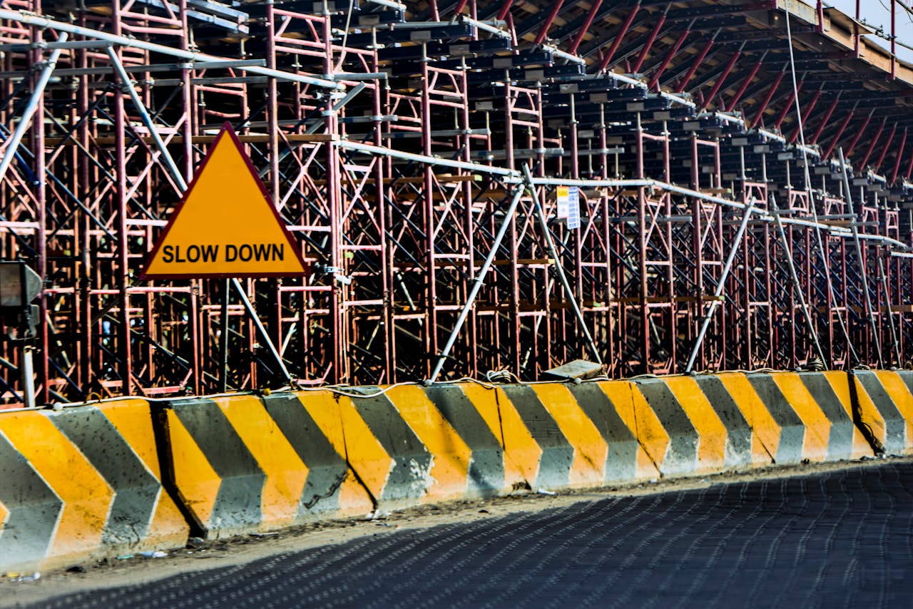 Construction site with a 'Slow Down' sign amid scaffolding in Kuwait.